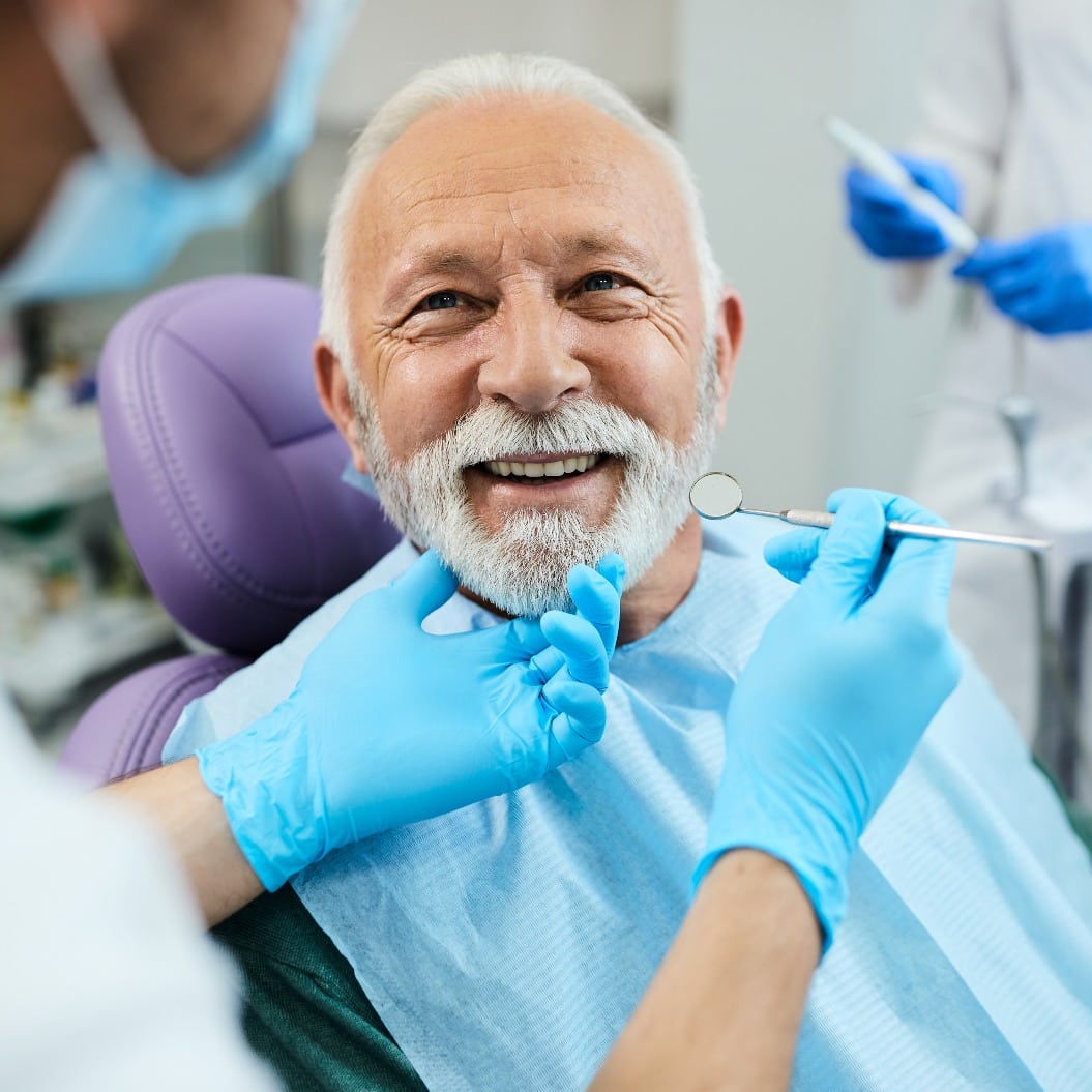 Happy senior man having dental treatment at dentist's office.
