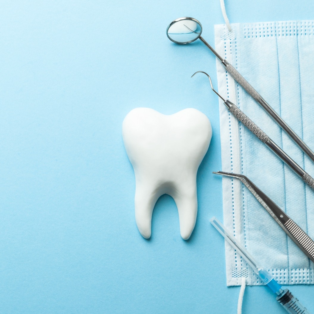 Tooth and dental instruments on blue background. Dental treatment. Dentist tools mirror, hook, tweezers, syringe. Copy space for text.